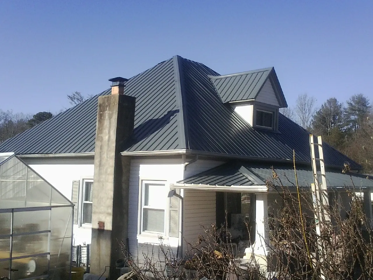 Dark blue standing seam metal roof on a white farmhouse with dormer — Slate & Tile Roof Repair by Roofing Brothers in Alameda
