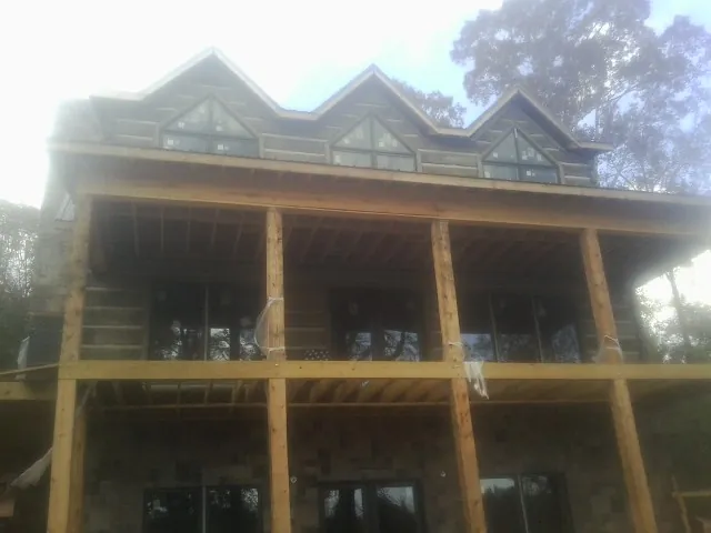 Dormers and porch framing on a large log home under construction — Roof Coating work by our crew in Alameda
