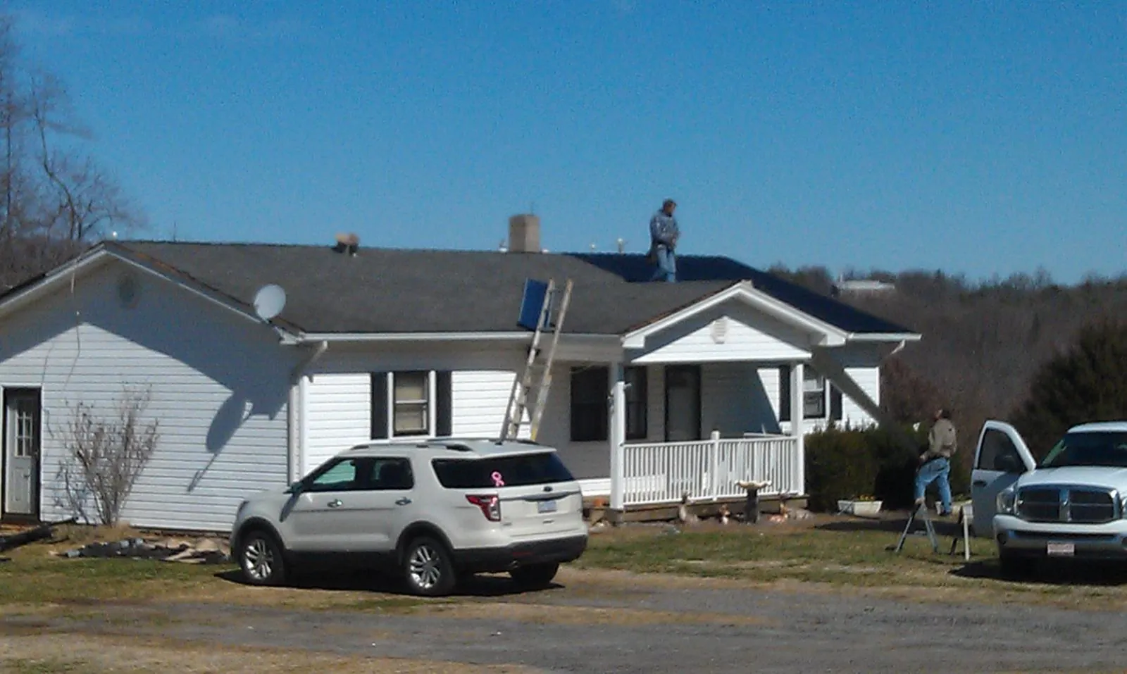 Roofers stripping shingles from a white ranch house roof in Alameda
