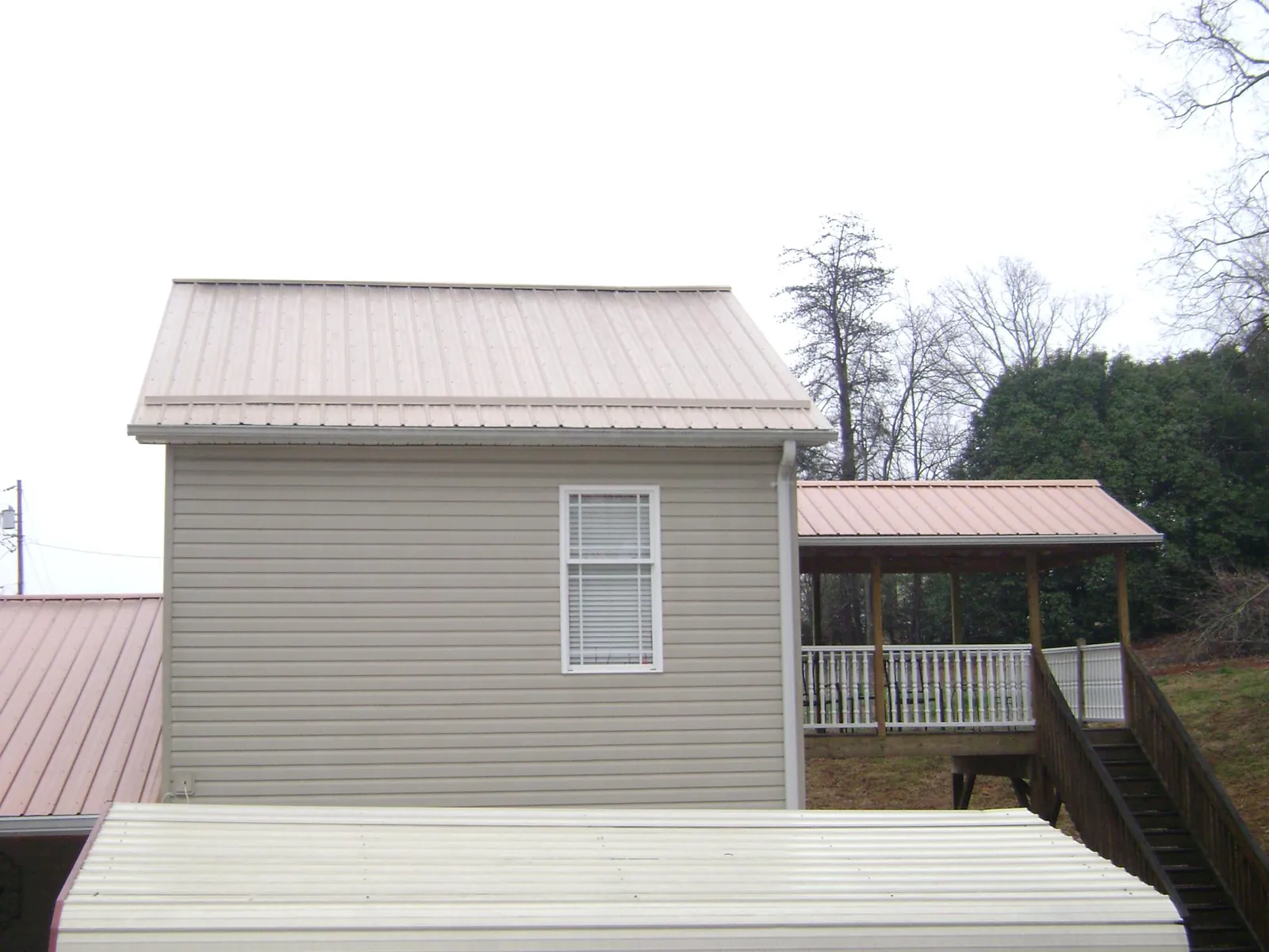 Tan metal roofs on a two story addition and attached porch, from a Roof Replacement job in Alameda